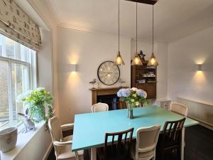 Un comedor con una mesa azul y un reloj. en Overton - Elie, en Elie