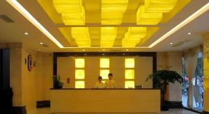 two people standing at a counter in a lobby at Super 8 Hotel Quanzhou Xinchezhan Branch in Quanzhou