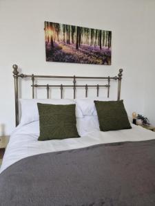 - un lit avec des draps blancs et 2 oreillers verts dans l'établissement NEWLY Refurbed - Large Studio Apt With Private Parking, à Exeter