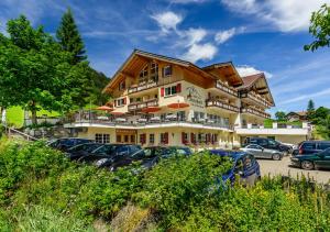 un bâtiment avec des voitures garées dans un parking dans l'établissement Hotel Steinbock, à Mittelberg