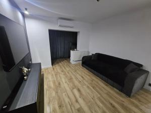 un soggiorno con divano nero e pavimento in legno di Promenada mall side a Craiova