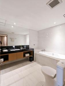 un bagno con vasca, WC e lavandino di Astanaraya Suites Hotel a Giacarta