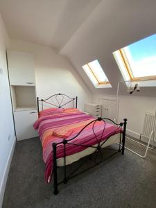 a bedroom with a bed with a pink blanket at EGHAM LOVELY STUDIO SELF CONTAINED 2 mins station in Egham