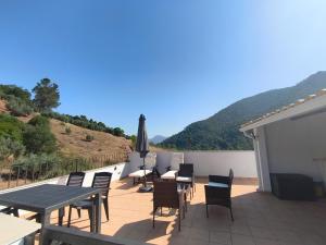 un patio con tavoli, sedie e un ombrellone di Alojamiento Rural El Lentisco 