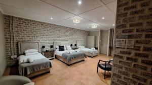 Un dormitorio con dos camas y una pared de ladrillo. en Mariental Hotel Cc, en Mariental