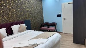a bedroom with a large bed and two chairs at Hotel Rashmi Grand in Khagaria