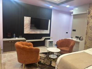 a bedroom with a bed and two chairs and a flat screen tv at Hotel Rashmi Grand in Khagaria