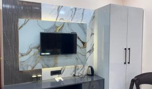 a living room with a tv on a wall at Hotel Rashmi Grand in Khagaria