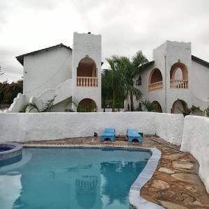 een zwembad met twee blauwe stoelen voor een huis bij 1Bedroom Villas- Serena, Mombasa in Mombasa