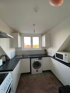 a kitchen with a washing machine and a microwave at EGHAM LOVELY STUDIO SELF CONTAINED 2 mins station in Egham