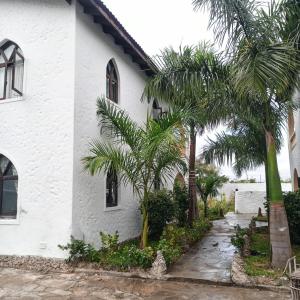 een wit huis met palmbomen ervoor bij 1Bedroom Villas- Serena, Mombasa in Mombasa