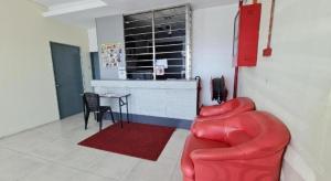 Una sala de estar con un sofá rojo y una mesa. en OYO 90442 Newtown Star Hotel, en Setia Alam