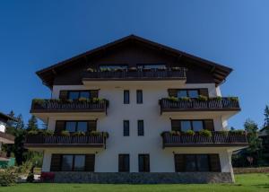 a white building with a black roof at Grand Chalet Ramina in Poiana Brasov