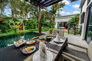 منتجع ذا بيل بول فيلا فوكيت في شاطئ كامالا: طاولة عليها طعام بجوار حمام سباحة