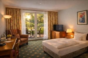 una habitación de hotel con una cama y un balcón en Parkhotel an der Therme, en Bad Krozingen