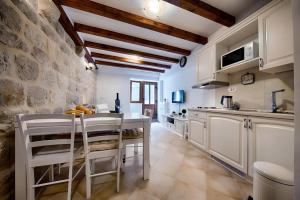 a kitchen with white cabinets and a stone wall at Riva Suite 1 in Komiža