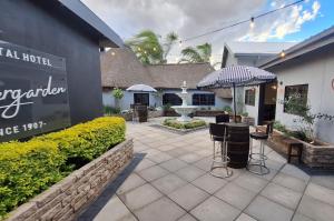 un patio con sillas y una sombrilla y un edificio en Mariental Hotel Cc, en Mariental