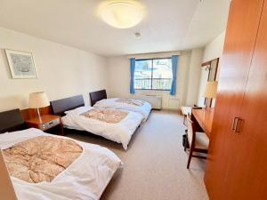 een hotelkamer met twee bedden en een bureau en een kamer met twee bij Powder Base Naeba in Yuzawa