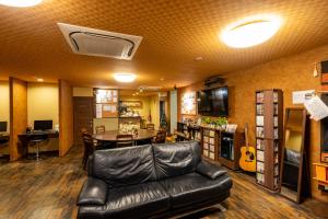 uma sala de estar com um sofá de couro e uma mesa em Guest House Ouka em Takayama