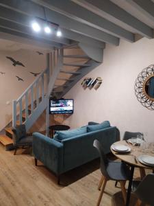 een woonkamer met een blauwe bank en een trap bij Cajem in Étretat