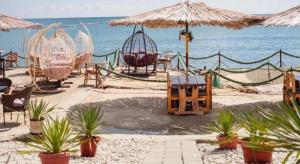 una playa con sillas y un columpio y el océano en OYO 90176 D'cruz Sunrise Villa, en Pantai Kok