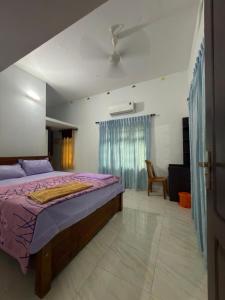 a bedroom with a bed with a purple comforter at Dream House Near IIM Kozhikode & NIT Calicut in Kozhikode