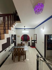 a living room with a table and chairs and a staircase at Dream House Near IIM Kozhikode & NIT Calicut in Kozhikode