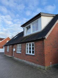 een rood bakstenen gebouw met twee ramen en een dak bij Hobro Living House in Hobro