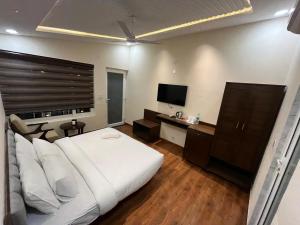a bedroom with a white bed and a television at Muchaan Resort in Gochar