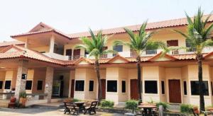a building with palm trees in front of it at Mark Four Place Hotel in Phrae