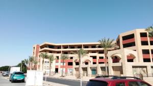 een rode auto geparkeerd voor een gebouw met palmbomen bij Luxury Studio, pool, Private beach & close to Airport in Hurghada