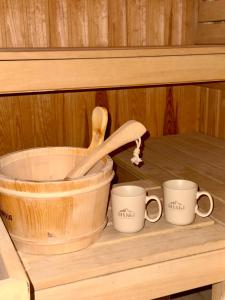 Un cubo de madera y dos tazas en un estante. en Divski Wellness Resort, en Divčibare