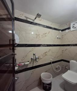 a bathroom with a toilet and a marble wall at Hotel Diamond Place in Khātu