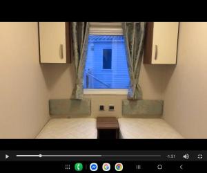 een kamer met twee bedden en een raam bij Sam's Caravan Hire Coastfield Holiday Village Ingoldmells in Ingoldmells