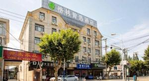 a large building on a city street with trees at GreenTree Inn Shanghai Luojing Express Hotel in Luojing