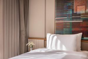 a bed with a white pillow in a room at Na U Hotel in Chiang Mai
