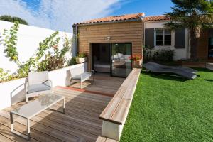 a deck with two chairs and a bench on the grass at ré tour de plage in Saint-Martin-de-Ré