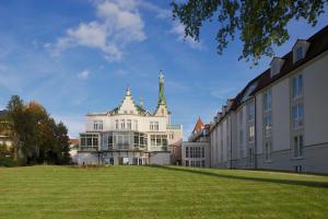 un gran edificio blanco con una torre en la cima de un campo en Dorint Parkhotel Meißen, en Meißen