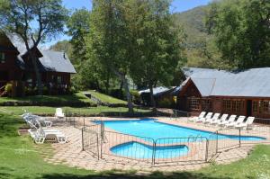 einem Pool vor einem Haus mit Stühlen und einem Gebäude in der Unterkunft Añañucas III in Las Trancas