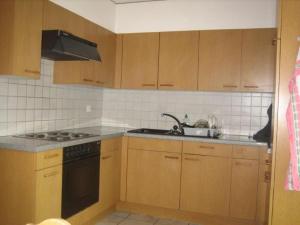 una cucina con mobili in legno e un forno a piano cottura di Unterkunft Zwisa a Jenaz