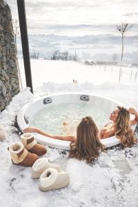 Twee vrouwen liggen in een jacuzzi in de sneeuw. bij Sense Resort in Maruszyna