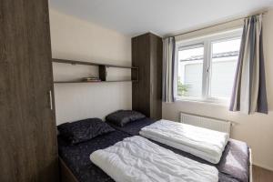 a bedroom with two beds and a window at Vakantiepark de Boomgaard in Westkapelle +148 photos