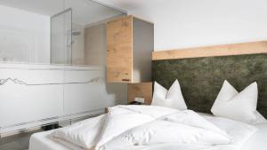 a bedroom with a bed with white sheets and pillows at das MOOSWALD in Obsteig