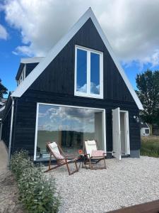 une maison noire avec deux chaises devant dans l'établissement Studio34, à Hauwert