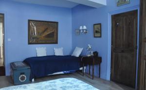 ein blaues Schlafzimmer mit einem Bett und einem Tisch in der Unterkunft Vaste chambre au centre du bourg in Saulieu