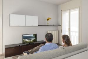 Ein Mann und eine Frau sitzen auf einer Couch und sehen fern. in der Unterkunft Casa Celeste in Pella