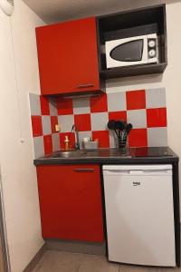 a small kitchen with red cabinets and a microwave at Pleasant, cozy studio with pool 2 mins from Montpellier in Juvignac +5 photos