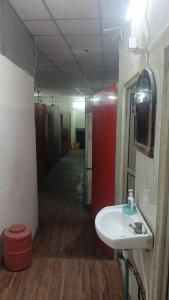 PrayagrajMaa Godawari Lodge的一间带洗手池的浴室和一条带隔间的走廊