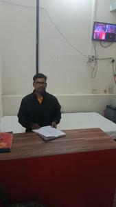 PrayagrajMaa Godawari Lodge的坐在桌子上的人,手提电脑