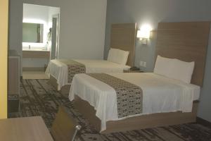 Una habitación de hotel con dos camas y un lavabo. en Hotel Royale IAH Airport North Houston I-45, en Houston